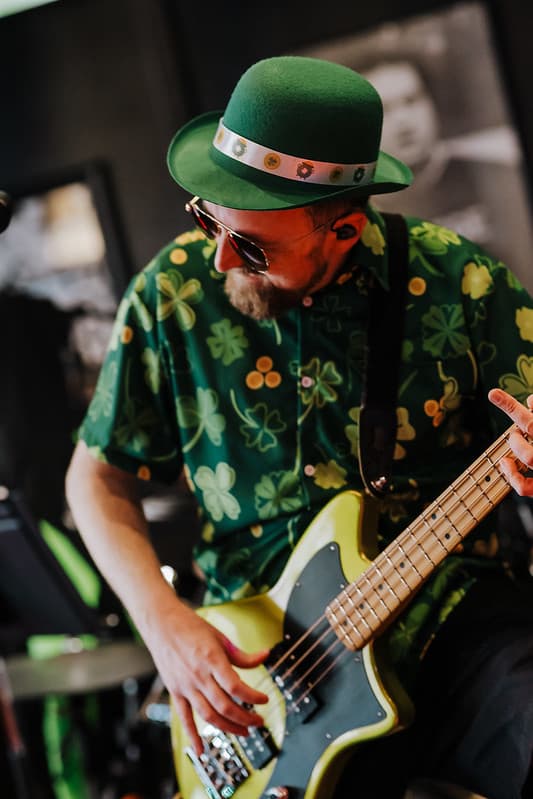 Bassist in shamrock shirt focused on the groove