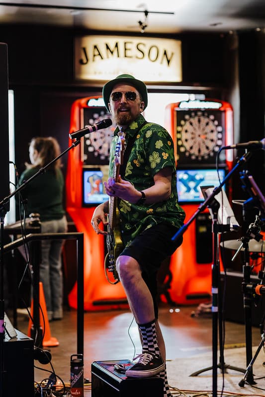 Guitarist in shamrock shirt rocking out at St. Patrick's Day show