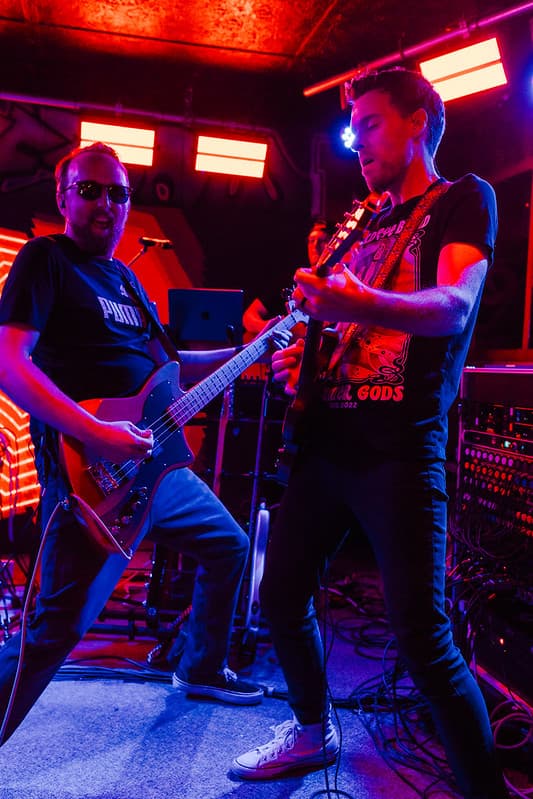 Bassist and guitarist jamming under neon red glow