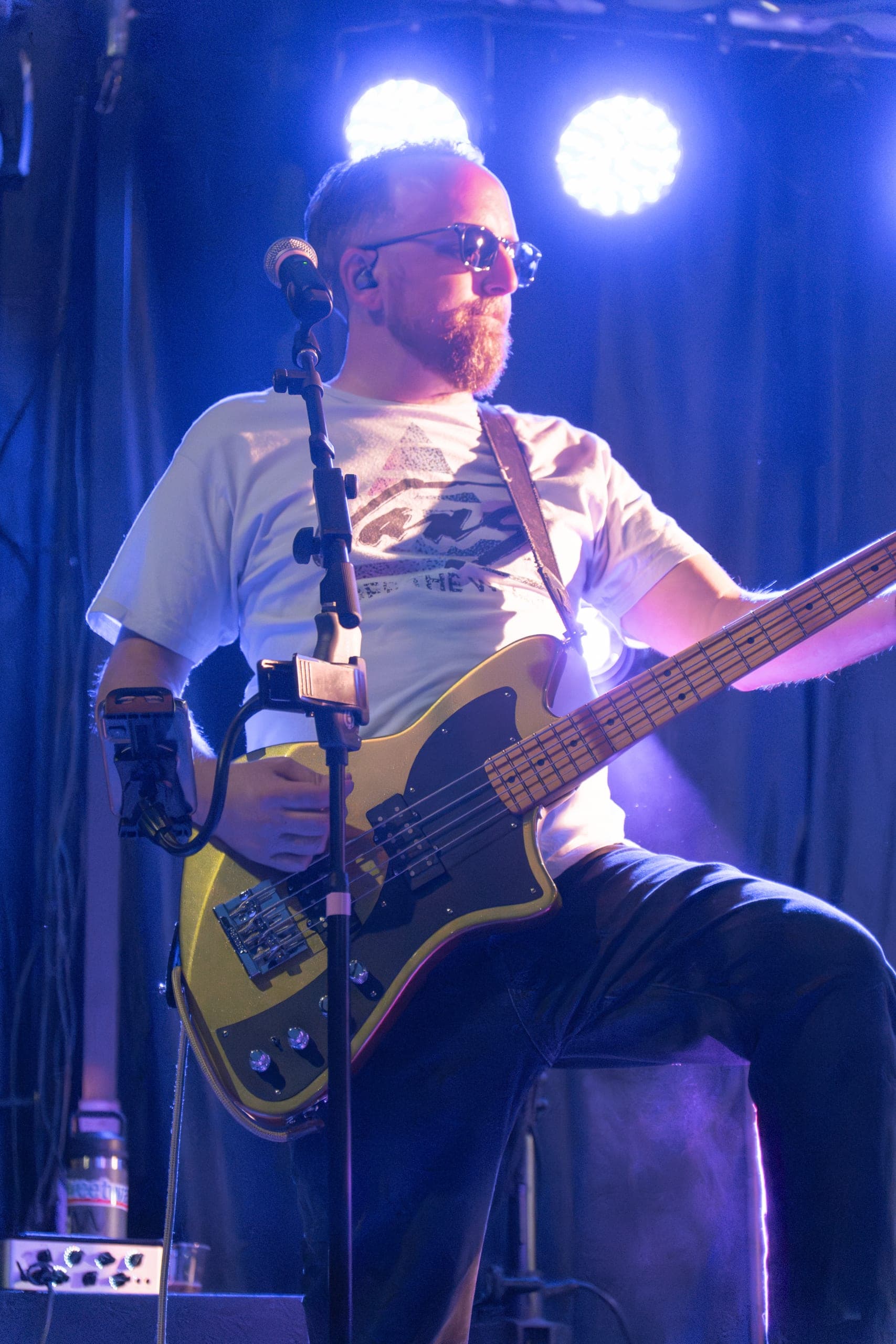 Bassist in sunglasses locking into the groove on a gold bass