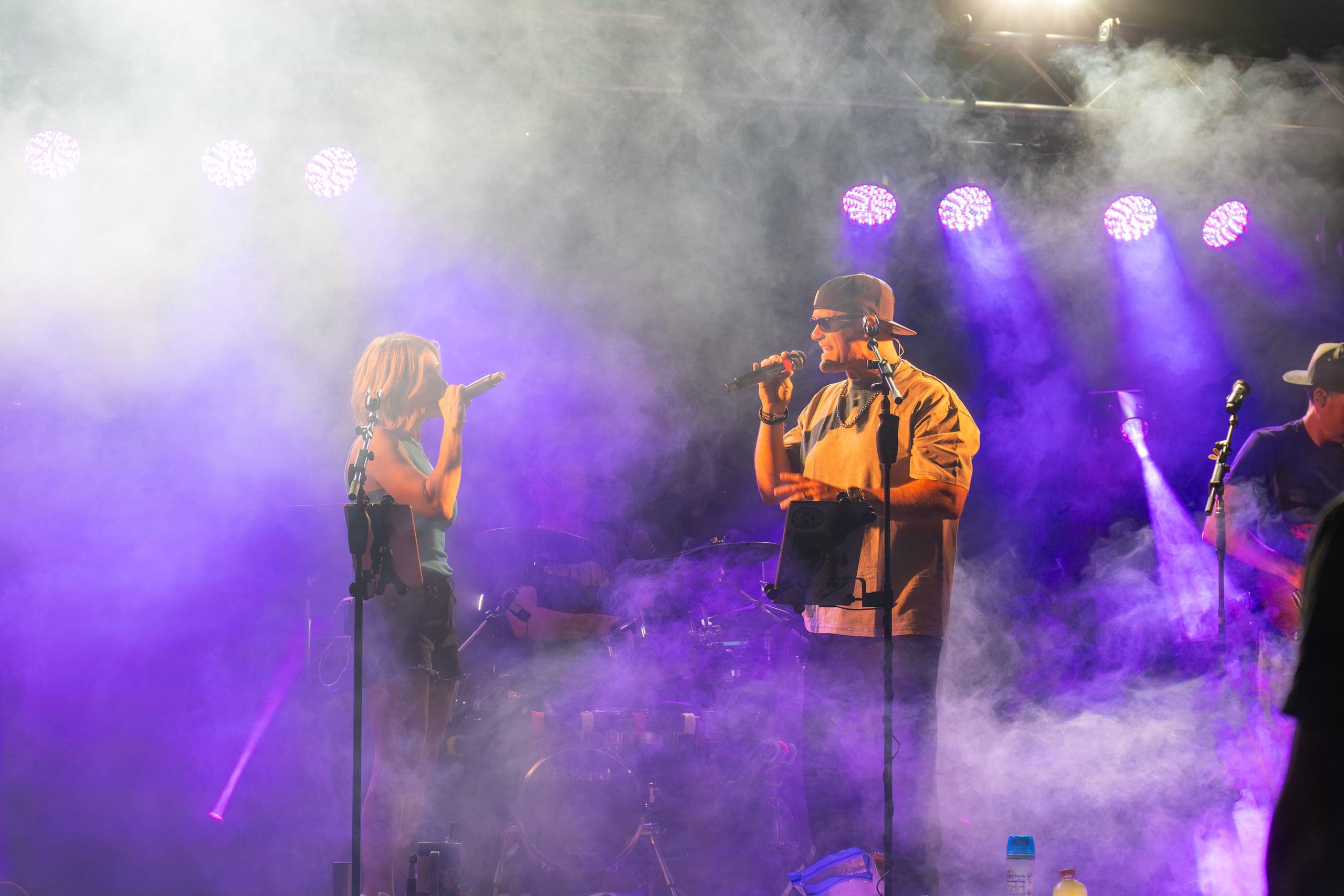 Two vocalists trading lines through a haze of purple stage light